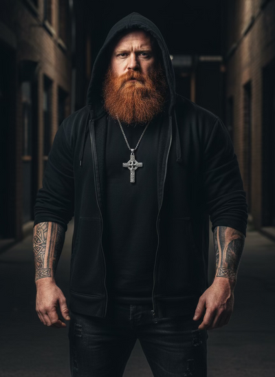 Man with a beard and tattoos wearing a black hoodie in an urban setting