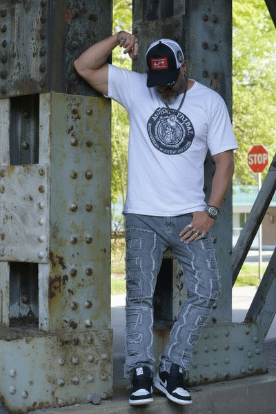 Ancient Tribal Dude in white t-shirt and jeans leaning against a metal structure